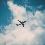 Shot from below of an airplane flying with clouds in the sky