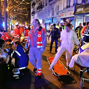 People rest on a bench after being evacuated from the Bataclan theater after a shooting in Paris, Saturday, Nov. 14, 2015.
