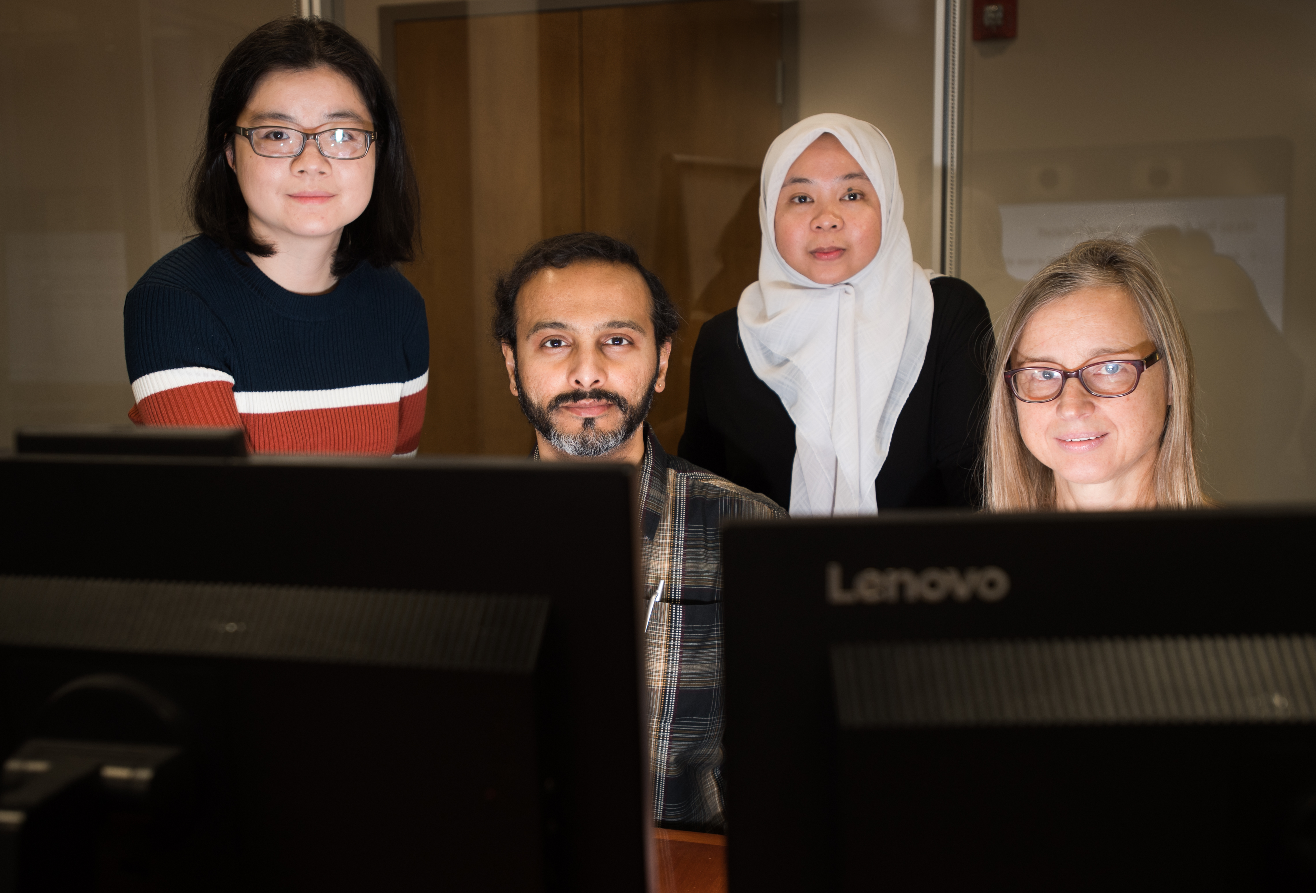 Photo of Lei Guo, from left, Prakash Ishwar, Derry Wijaya, and Margrit Betke in front of computer monitors.