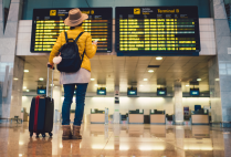 young woman standing in front of a boarding schedule in an airport