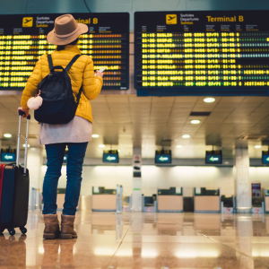 young woman standing in front of a boarding schedule in an airport