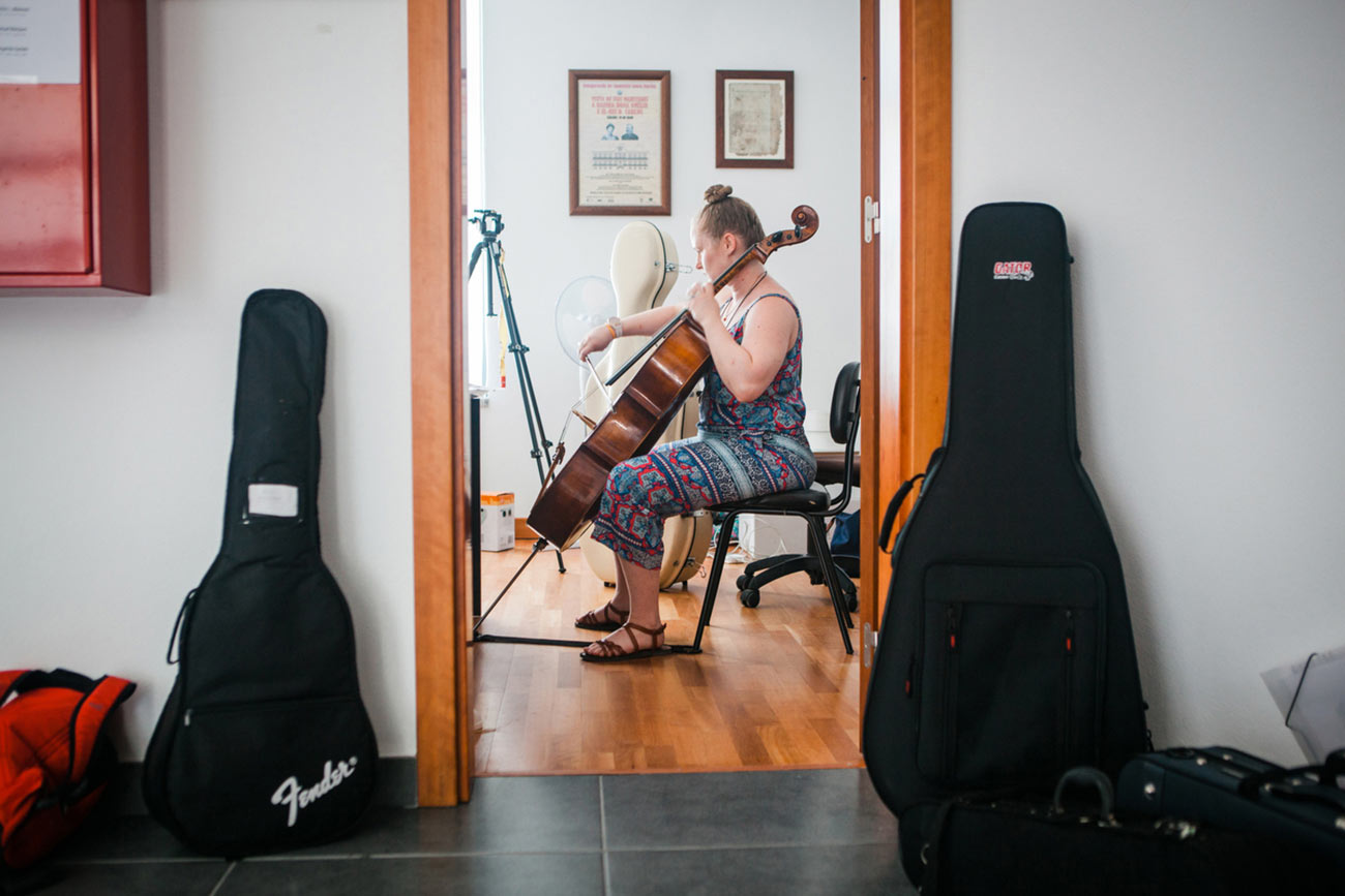Full color slideshow photo of Cello instructor and Boston University student Gracie Keith practicing in the office of the Casa Da Musica Da Bendada.