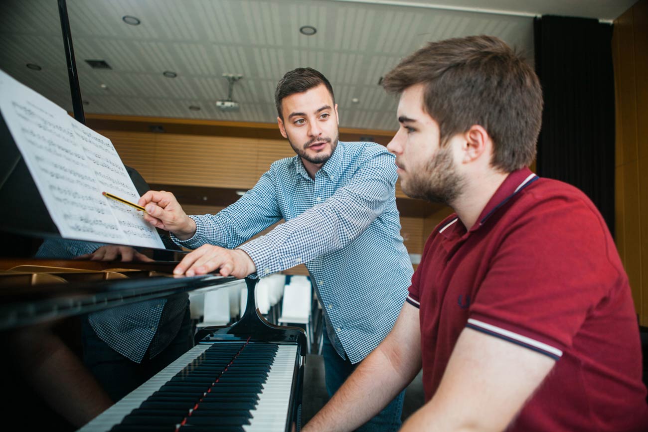 Full color slideshow photo of Boston University student Edoardo Carpenedo, a Bendada Music Festival co-founder and instructor, leading a piano lesson with a student from Fundão, Portugal.