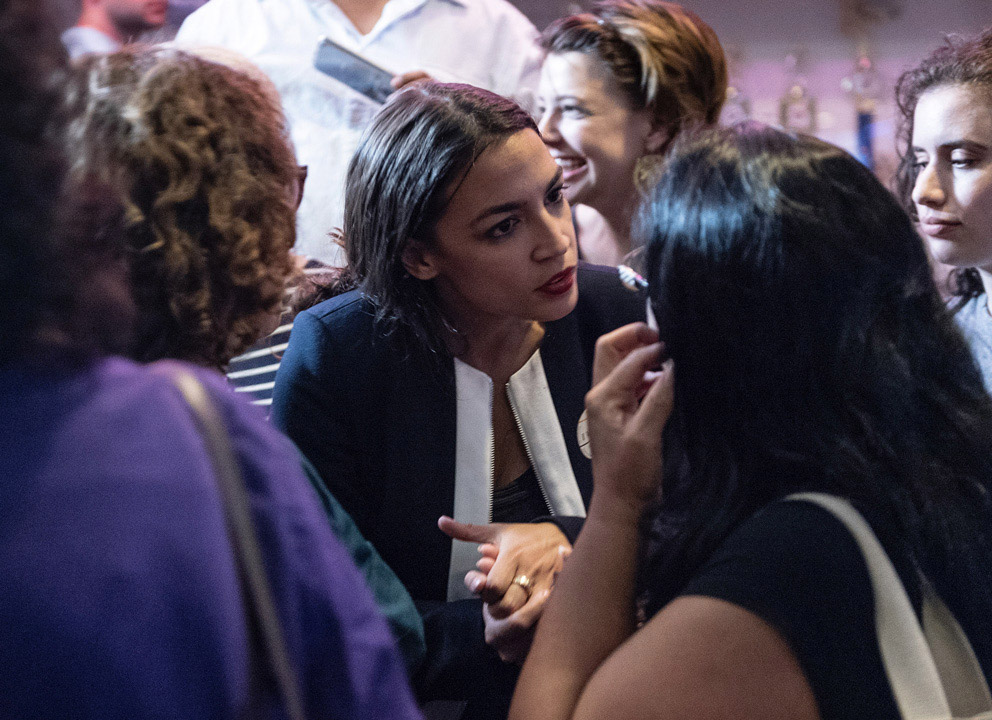 Alexandria Ocasio-Cortez, candidate for the House of Representatives from New York's 14th District, talks to a supporter in a crowd.