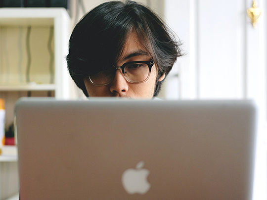 Man with glasses looking at a computer