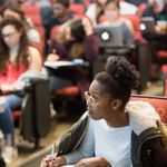 Young black woman taking notes in a lecture hall