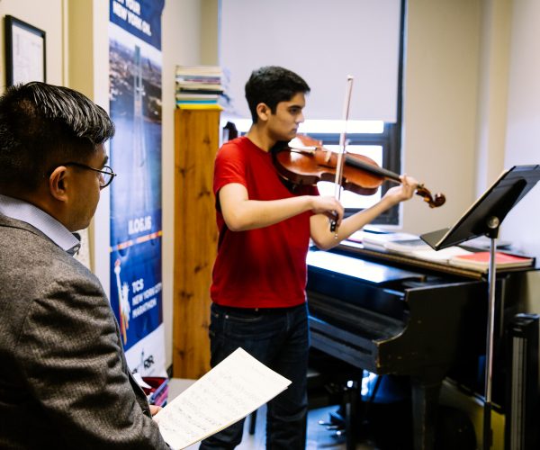 Music instructor watching student play the violin