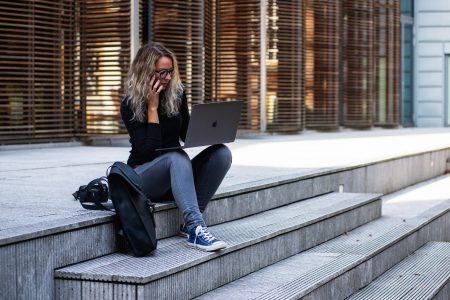 A woman sitting on steps with a laptop and phone
