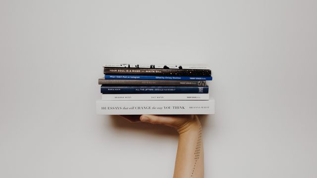 A hand holdng a stack of books