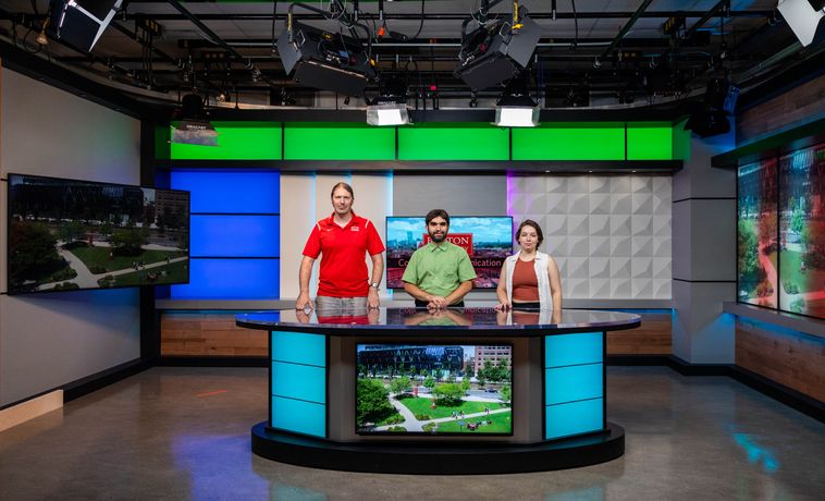 Tristan Olly (lead studio engineer), Jake Kassen (technical operations manager) and Emma Picht (COM ’23) (media technician) pose at the new anchor desk in Studio West. Photo by Guramar Lepiarz.