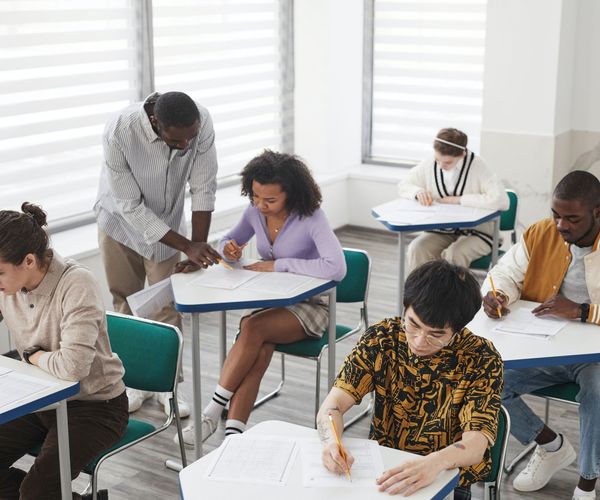 Group of students working in class. Professor is helping one of them.