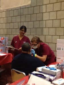 Carol Patel and Casey Mauder, both DMD 16, perform an oral screening on a veteran