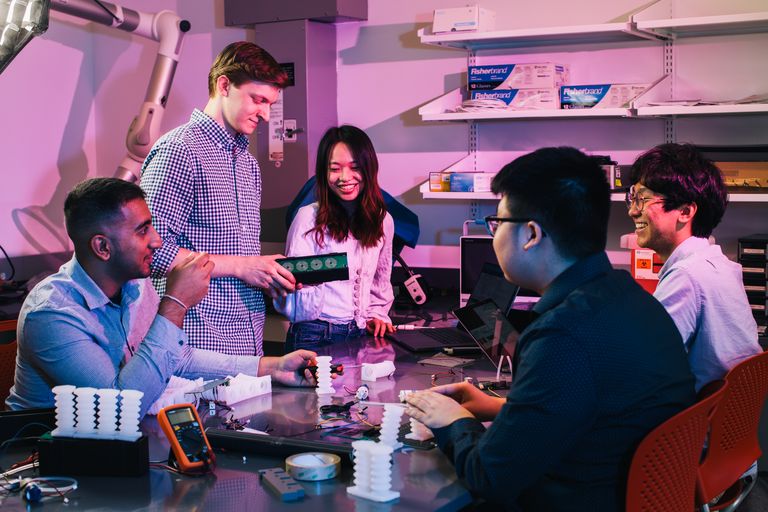 Group of Engineering students working together around a table in a lab setting