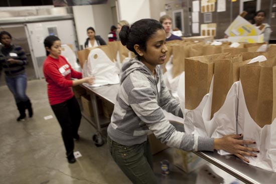 Boston University student Arthrika Chandramohan puts together packages of food at "Food and Friends" food bank in NE Washington. 