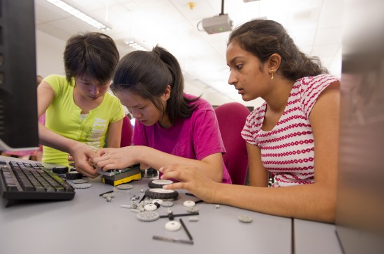 Shirley Zhou, of Jamaica Plain, Erica Yuen, of Winchester, and Suma Anand, of Newton, build Spaz, their LEGO MINDSTORMS robot. Photo by Cydney Scott.