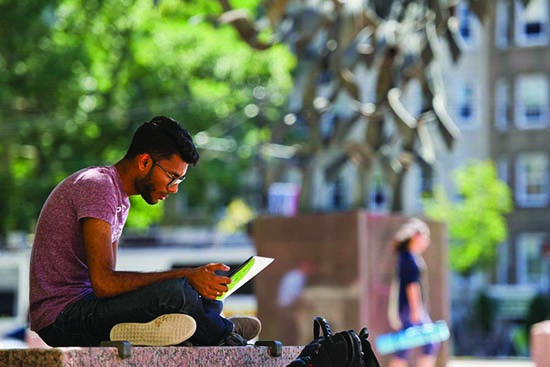 Student sitting in Marsh Plaza, BU Beach, Boston University