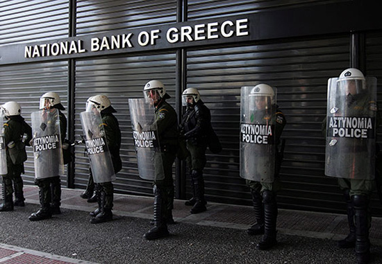 Police guard a Greek bank earlier this year during protests by striking Greek workers against continued government austerity.