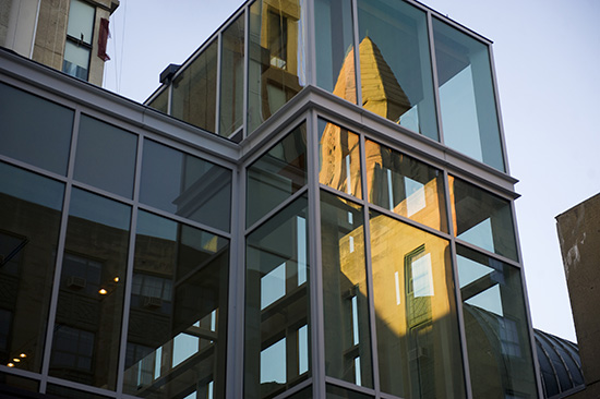 CAS tower reflects in the glass of the new The Sumner M. Redstone building in the evening light