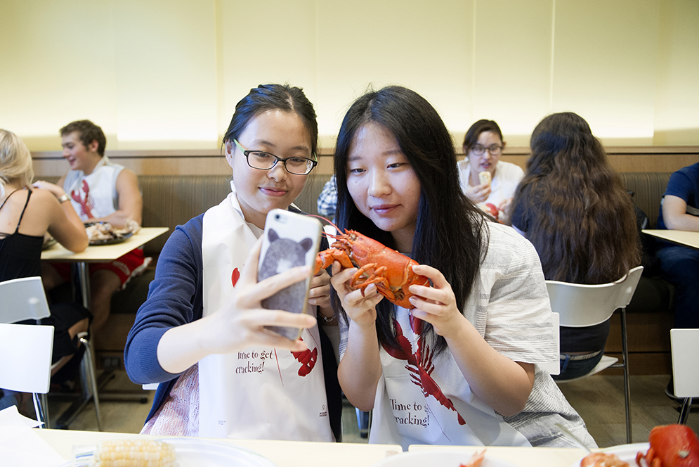 Sipei Fu (SAR'19) , left and Jie Ling (COM'19) take a selfie with a lobster during lobster night at Marciano Commons on Wednesday, September 16, 2015. Photo by Jackie Ricciardi