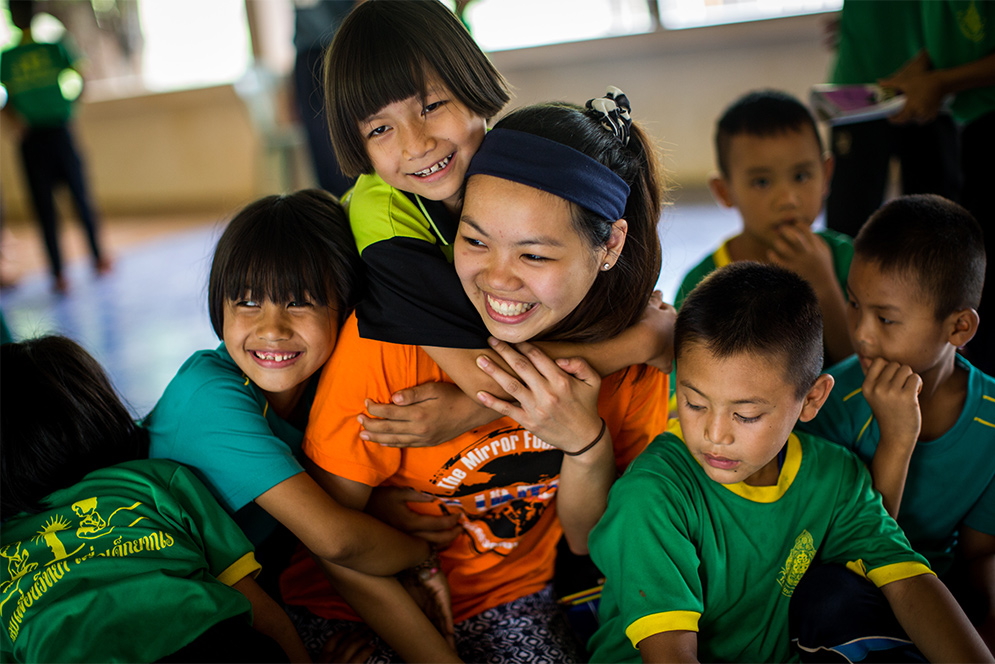 BU Sargent College student Grace Lei is hugged by children during a public health education trip to Ban Doi Chaang village in Thailand