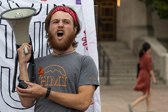 Matt Thacker holds a blow horn at the Divestment Rally at Marsh Plaza