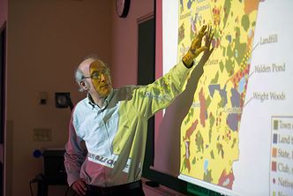 Richard Primack in a classroom giving a lecture in front of a projector screen