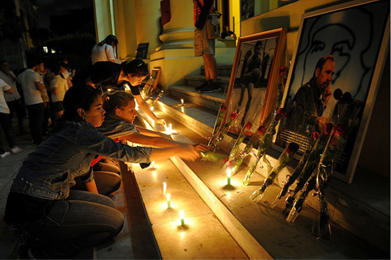 Cubans mourning light up candles in front of photos of Castro