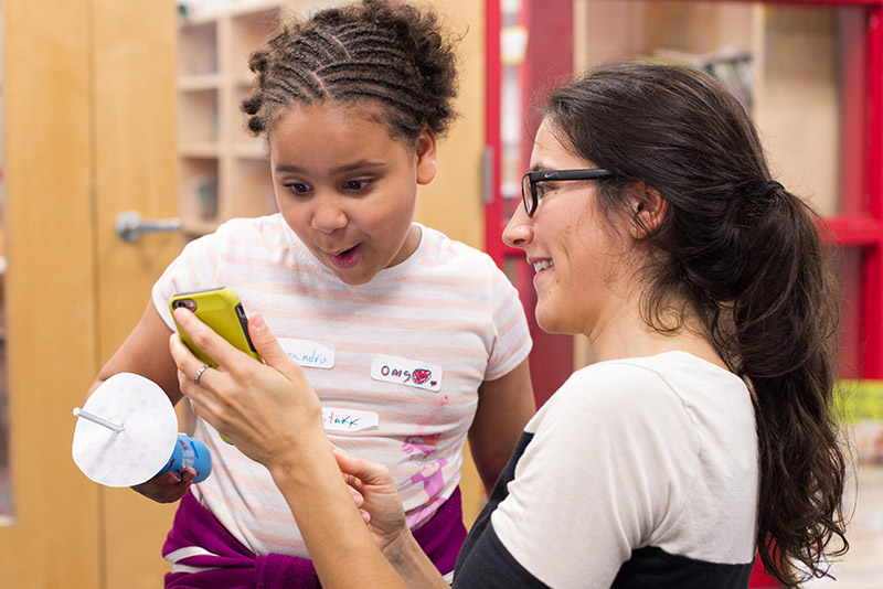 Angela Rigden and Cassandra Riley watching a video of the inside of the kaleidoscope Riley constructed for a Girls Science Club project.