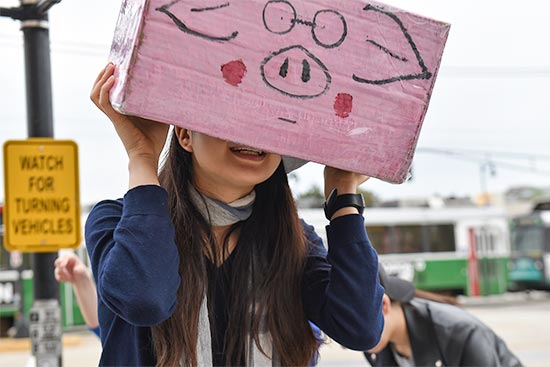 A student wears a pink pig pinhole camera made for an introductory photography class at Boston University