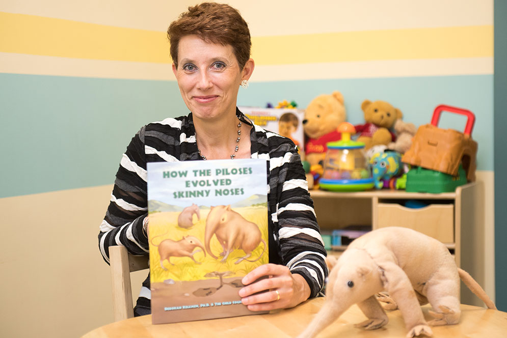 Deborah Kelemen holding her new children's book introducing the concept of adaptation by natural selection