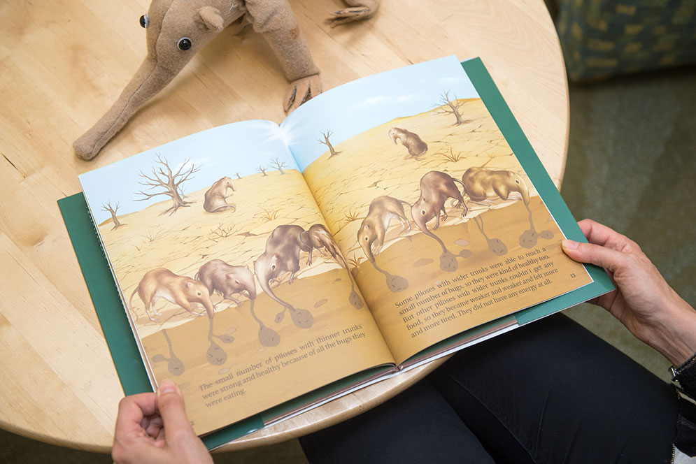 Deborah Kelemen holding her new children's book introducing the concept of adaptation by natural selection
