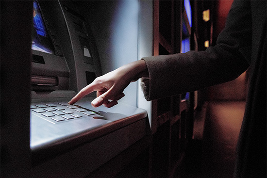 Female using an ATM at night