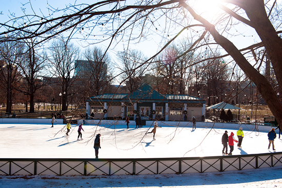 People Ice skating around Frog Pond on a sunny winter day. 