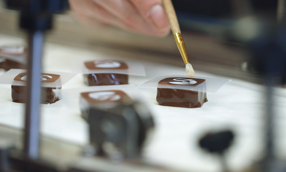 EHChocolatier founder Elaine Hsieh handpaints artisan chocolate on a conveyor belt