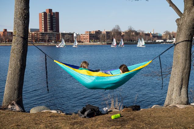 BU students relax in a hammock overlooking the Charles River