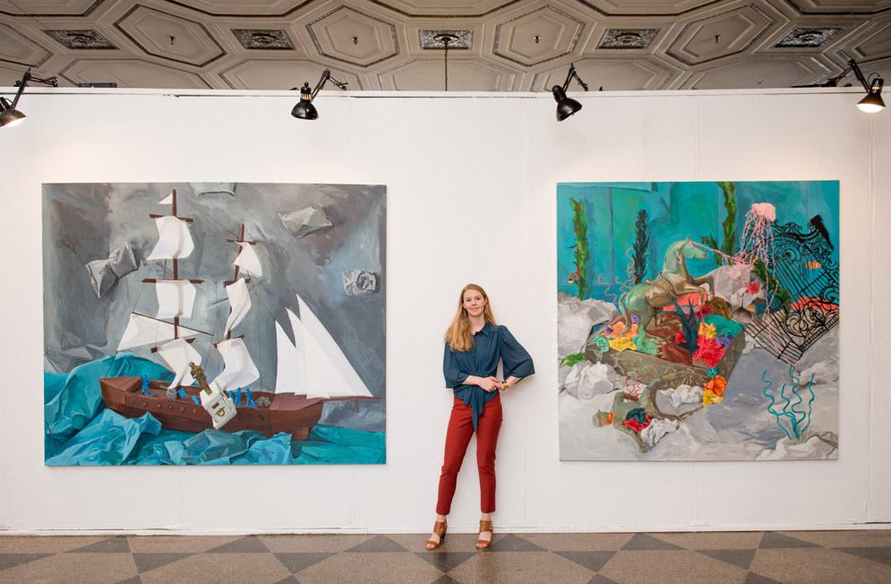 Arden Cone stands with her paintings