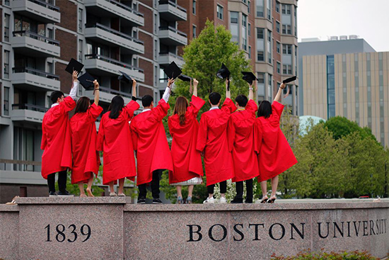 Graduating students of the Class of 2018 stand on top of the Boston University sign and wave goodbye to the University