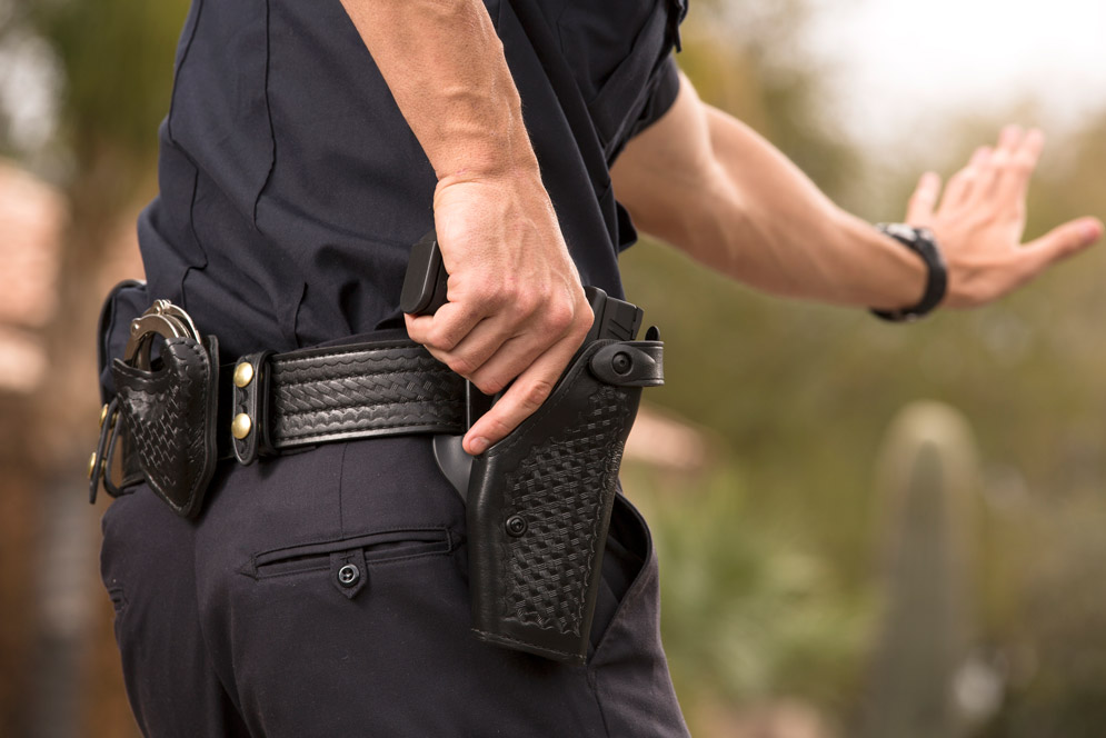 A police officer pulls his gun out of his holster