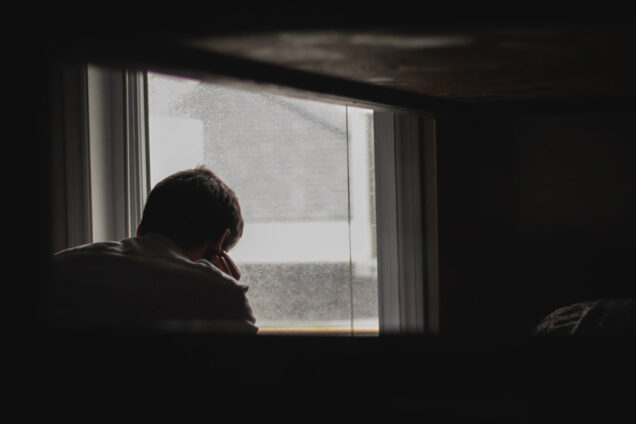 Depressed man stares out a window