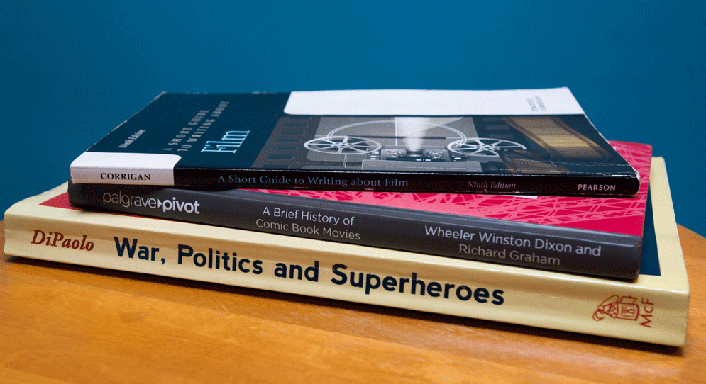 A pile of books including War, Politics and Superheroes, A Brief History of Comic Book Movies, and A Short Guide to Writing about Film