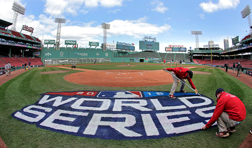 Grounds crew members paint the World Series logo behind home plate at Fenway Park, Sunday, Oct. 21, 2018, as they prepare for Game 1 of the baseball World Series.
