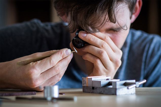 Mechanical Engineer Ian Schon of Schon Horology examines the tiny hand of a wristwatch he is making with a spectacle.