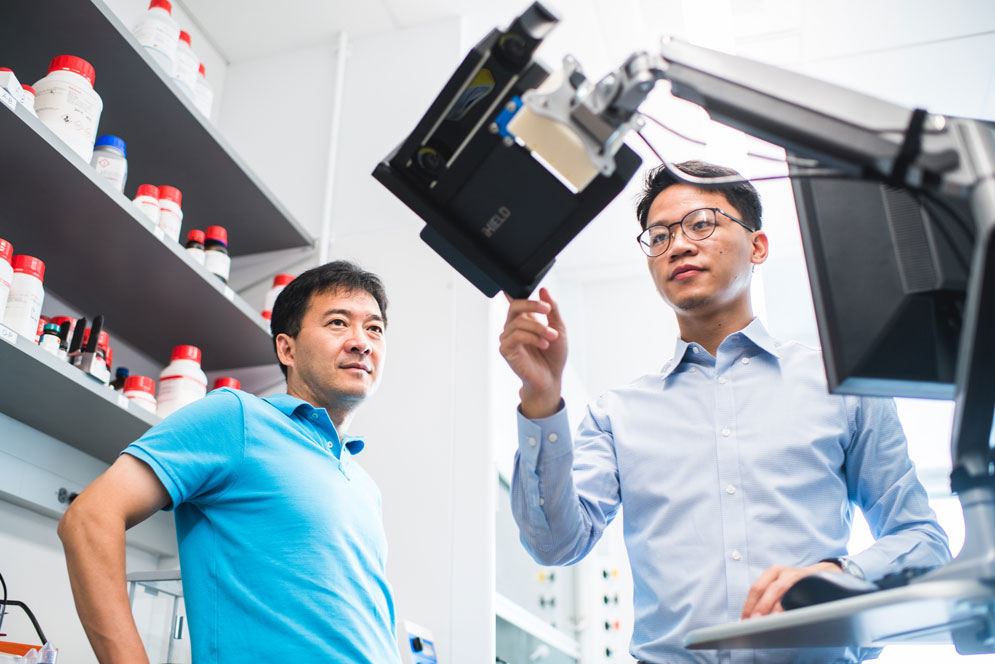 BU biomedical engineers Ji-Xin Cheng (left) and Lu Lan (right) monitor a tablet that displays AcouStar breast cancer tumor lumpectomy guidance to surgeons.