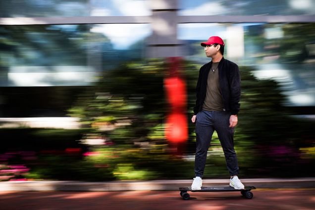 Student riding a penny board around campus