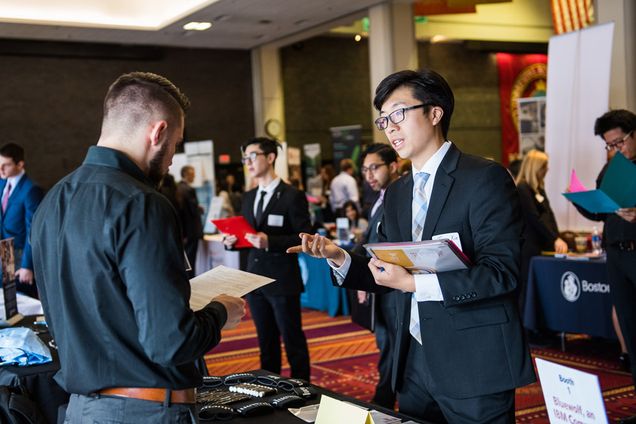 A student hands out a resume at an All-Majors Career Fair