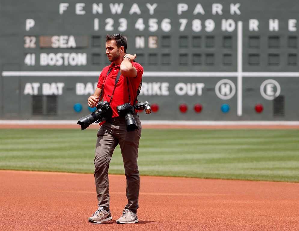 Billie Weiss, the Red Sox manager of photography, on the field wearing multiple cameras