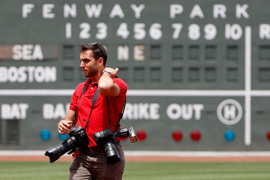 Billie Weiss, the Red Sox manager of photography, on the field wearing multiple cameras