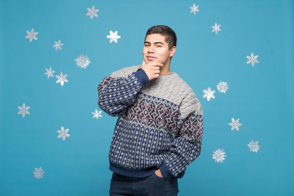 Augustine Jimenez poses in a snowflake-patterned sweater he got from Goodwill