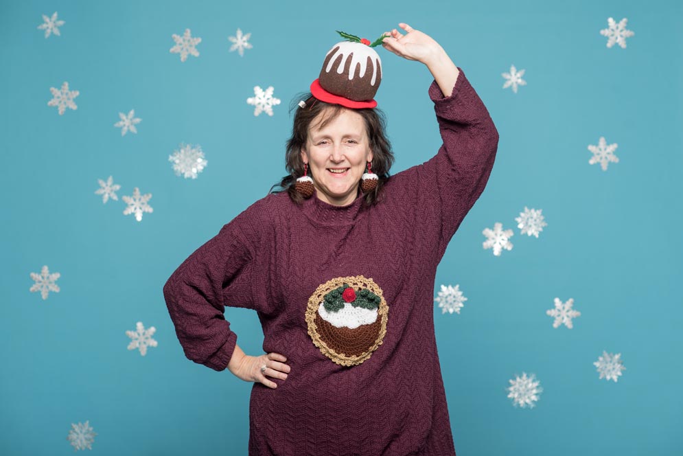 Regina Hansen wears a maroon sweater with a crocheted figgy pudding on it.
