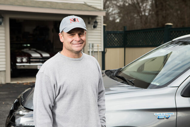 Portrait of Mike Wagner standing in front of his Mitsubishi Outland PHEV hybrid vehicle.